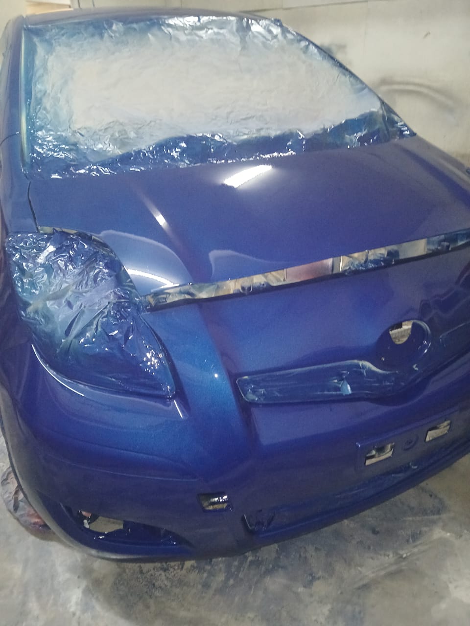 Toyota Yaris front end with deep blue metallic respray inside Mega Body Auto spray booth