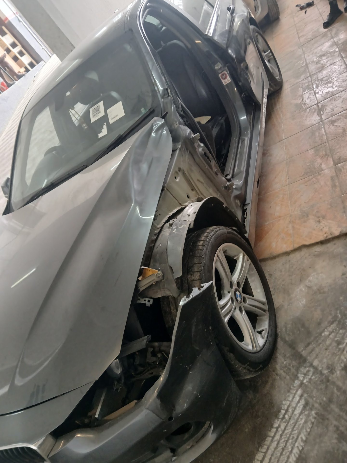 Silver BMW 1 Series with severe side-impact collision damage to driver side door and front fender, Maitland workshop